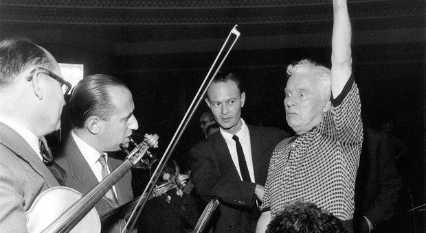 L'homme qui lève le bras, c'est Charles Chaplin. Sur la photo, il est en train de diriger les musiciens pour l'enregistrement de la musique de son film Un Roi à New York le 21 juin 1957 au Palais de la Mutualité à Paris. (© Rue des Archives/AGIP)