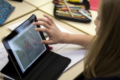 Sur cette photo, tu peux voir une élève qui travaille directement sur sa tablette. Elle n'a donc pas besoin de son stylo pour écrire. (© AFP PHOTO / FRED DUFOUR)