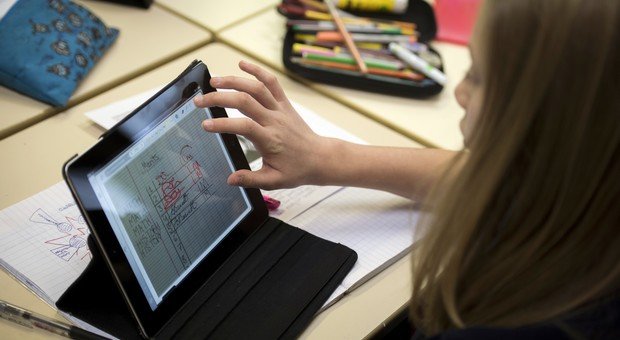 Sur cette photo, tu peux voir une élève qui travaille directement sur sa tablette. Elle n'a donc pas besoin de son stylo pour écrire. (© AFP PHOTO / FRED DUFOUR)