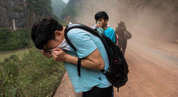 Les deux garçons que tu vois sur cette photo protègent leur visage de la poussière des chutes de pierre provoquées par le tremblement de terre. (© CHINA OUT AFP PHOTO)