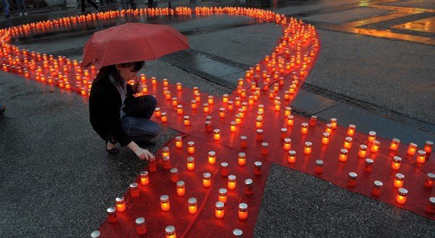 Sur cette photo, tu peux voir une femme qui allume une des bougies qui forment un ruban rouge. Ce ruban rouge symbolise la lutte contre le sida.( © AFP PHOTO / ALEXA STANKOVIC)
