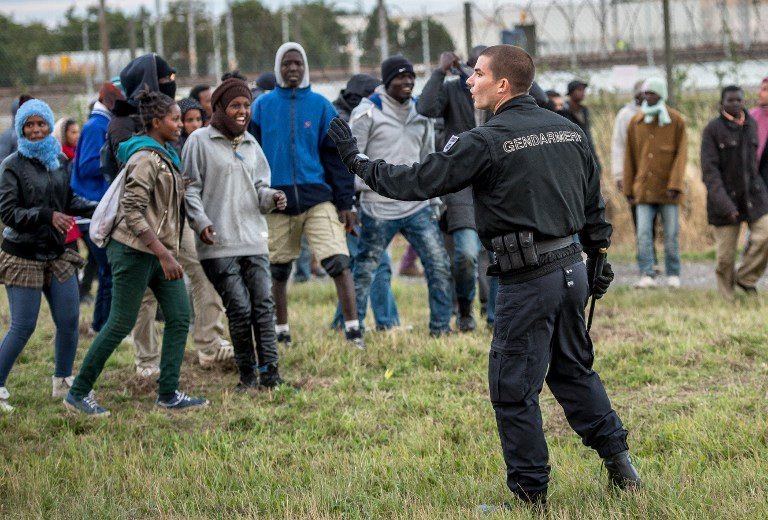 À Calais, un policier tente d'empêcher les migrants de rejoindre le tunnel sous la Manche pour gagner le Royaume-Uni. © Philippe Huguen/ AFP