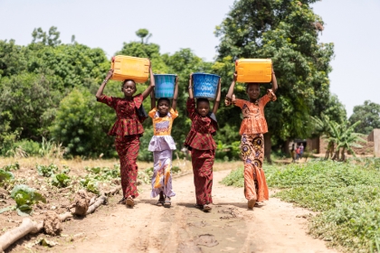 jeunes filles africaines portant des bassines d'eau sur leur tête.