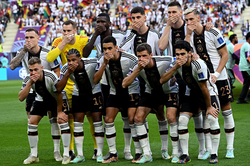 l'équipe de footballeurs allemands posant pour la photo officielle une main sur la bouche en signe de silence forcé.