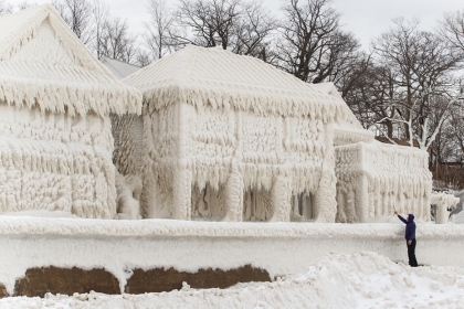 Une personne prend en photo des maisons recouvertes de glaces du toit au sol à Fort Érié au Canada