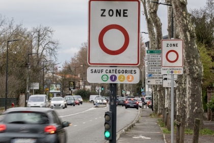 photo d'une route en ville avec un panneau annonçant une ZFEm et les vignettes crit'air autorisées