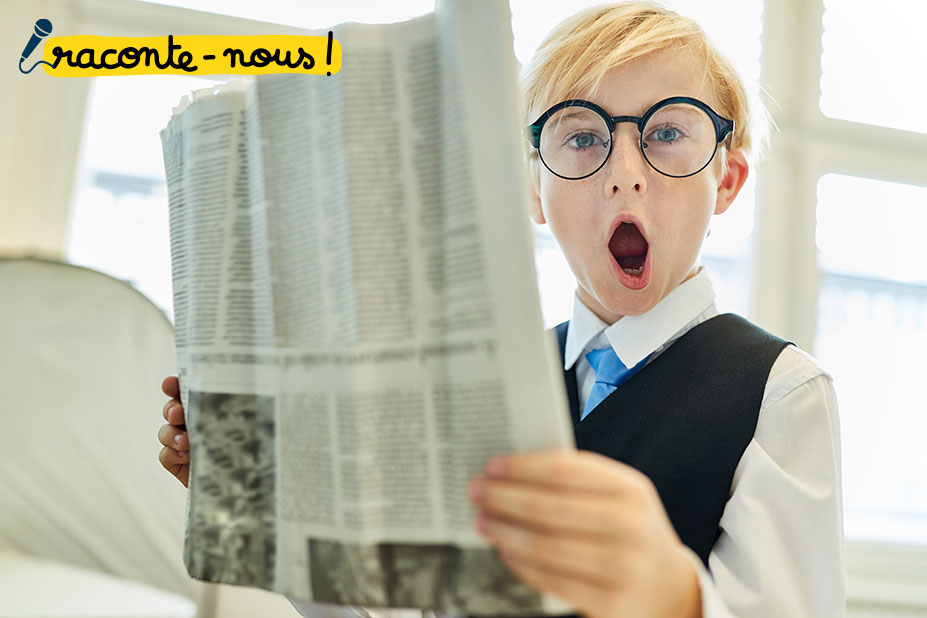 un enfant habillé comme un grand (chemise, gilet et cravate) lit le journal. Il fait une moue amusante comme s'il était choqué par ce qu'il lit