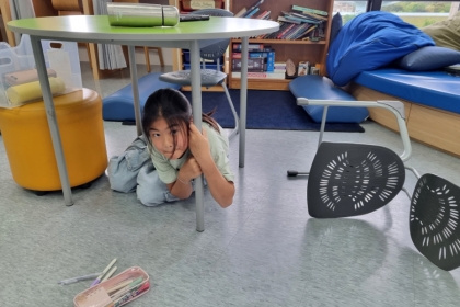 Anabel se protège d'un séisme en se cachant sous une table à l'école.