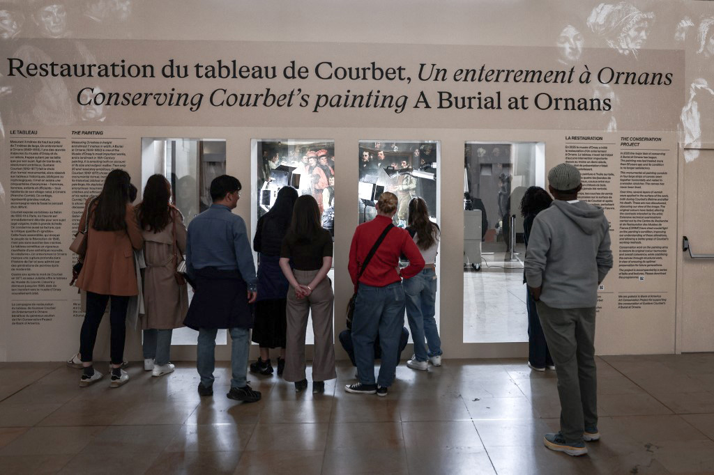 Les visiteurs sont invités à entrer dans la salle où se trouve le tableau en cours de restauration.