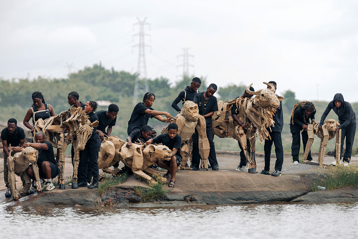 Photo montrant les animaux de cartons et leurs manipulateurs au bord de l'eau, à Kinshasa au Congo
