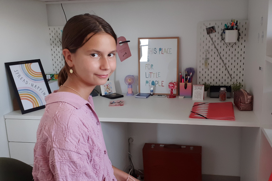 Jade, 10 ans, assise devant son bureau.