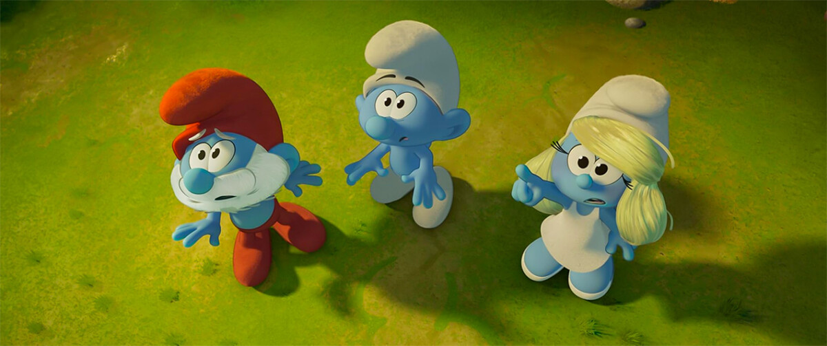 Trois Schtroumpfs, dont le Grand Schtroumpf, regardent vers le haut sur une pelouse.