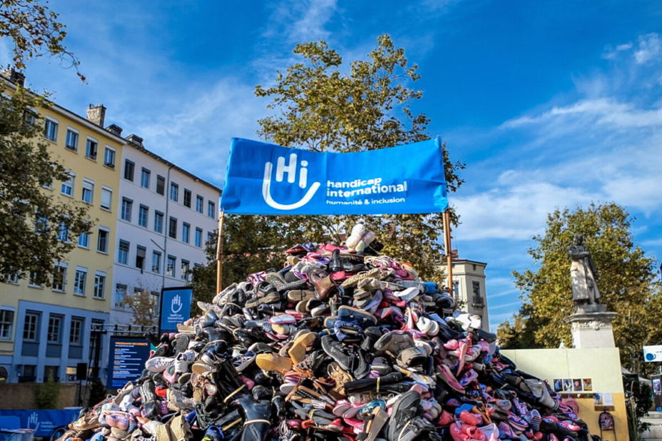 Une grosse montagne de chaussures réhaussée par une banderole d'Handicap International