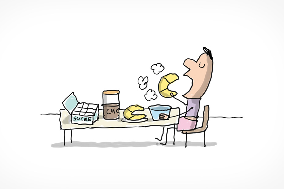 Un enfant prend son petit-déjeuner assis à table. Il s'apprête à croquer dans un croissant. Sur la table on voit un bol de chocolat chaud, une banane, un pot de cacao et une boite de sucre.